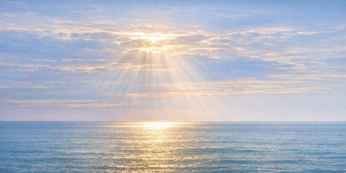 Sunrays shining through soft clouds onto a calm ocean, illustrating themes of clarity and grounding for parents experiencing estrangement.